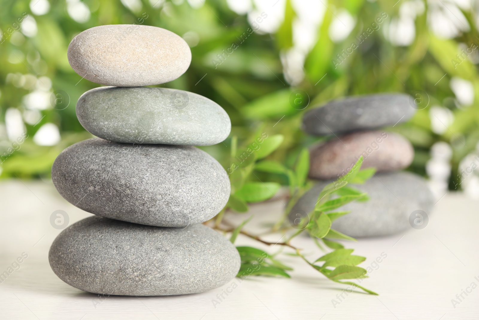 Photo of Spa stones and bamboo leaves on table against blurred background. Space for text