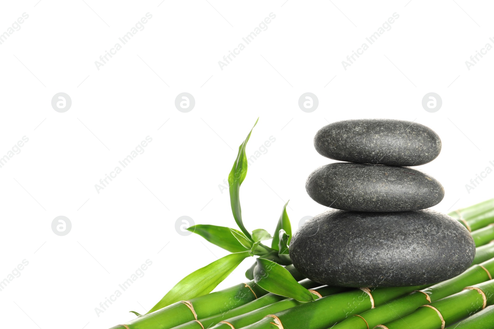 Photo of Stack of spa stones on bamboo stems against white background