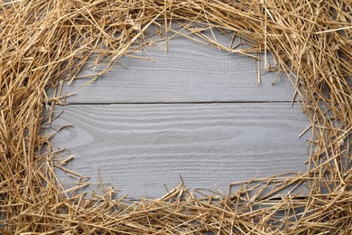 Photo of Frame of dried straw on grey wooden table, top view. Space for text