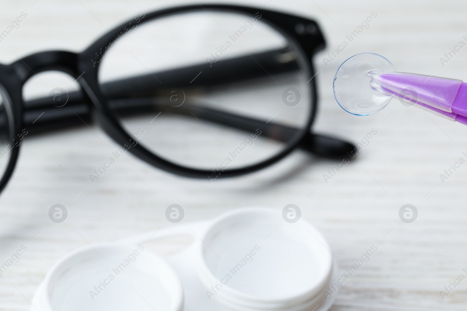 Photo of Tweezers with contact lens over case, closeup