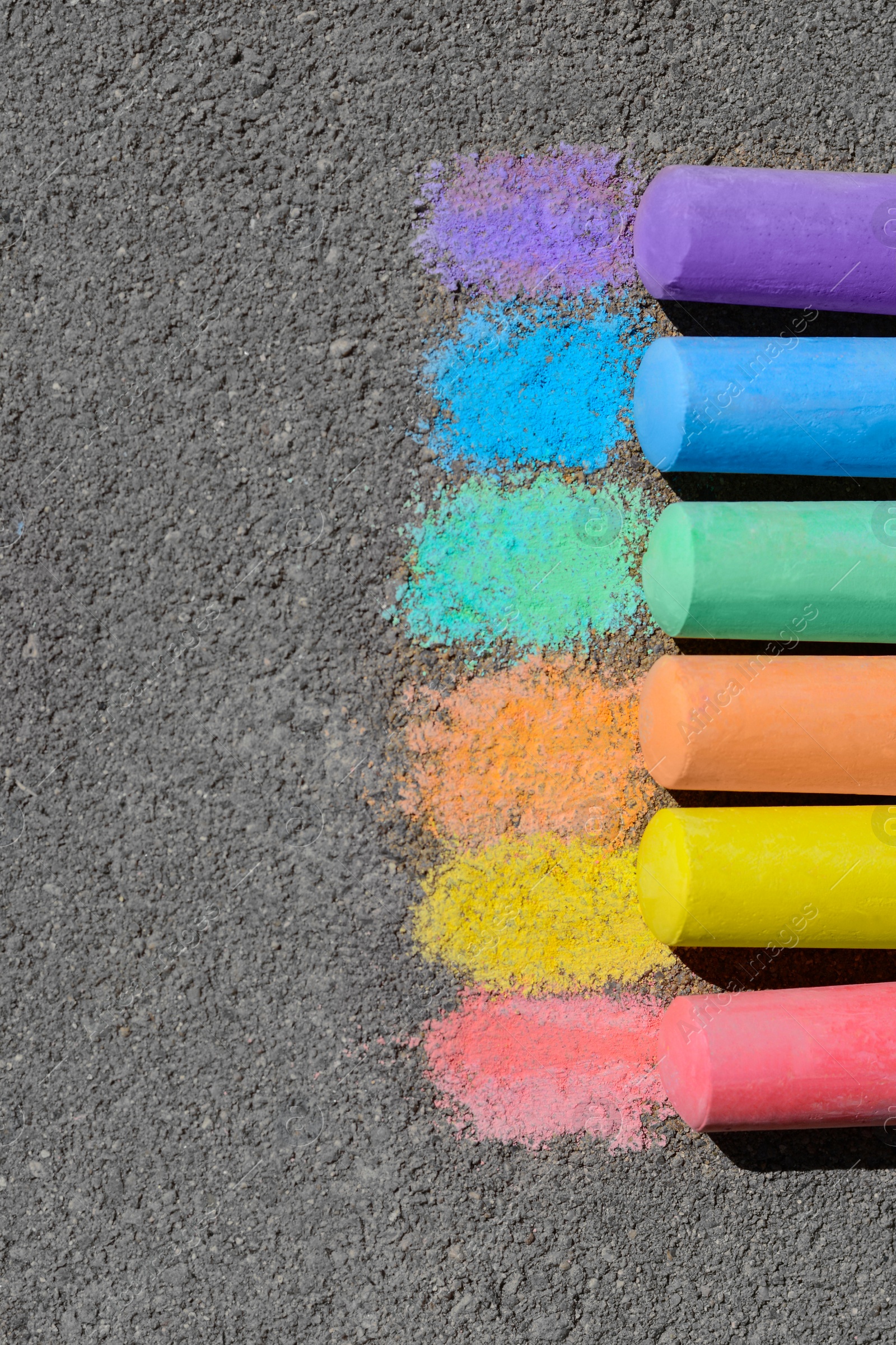 Photo of Colorful chalk sticks on asphalt outdoors, flat lay. Space for text