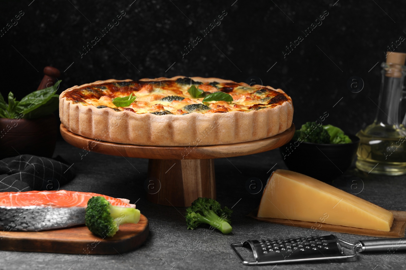 Photo of Delicious homemade quiche and ingredients on black table