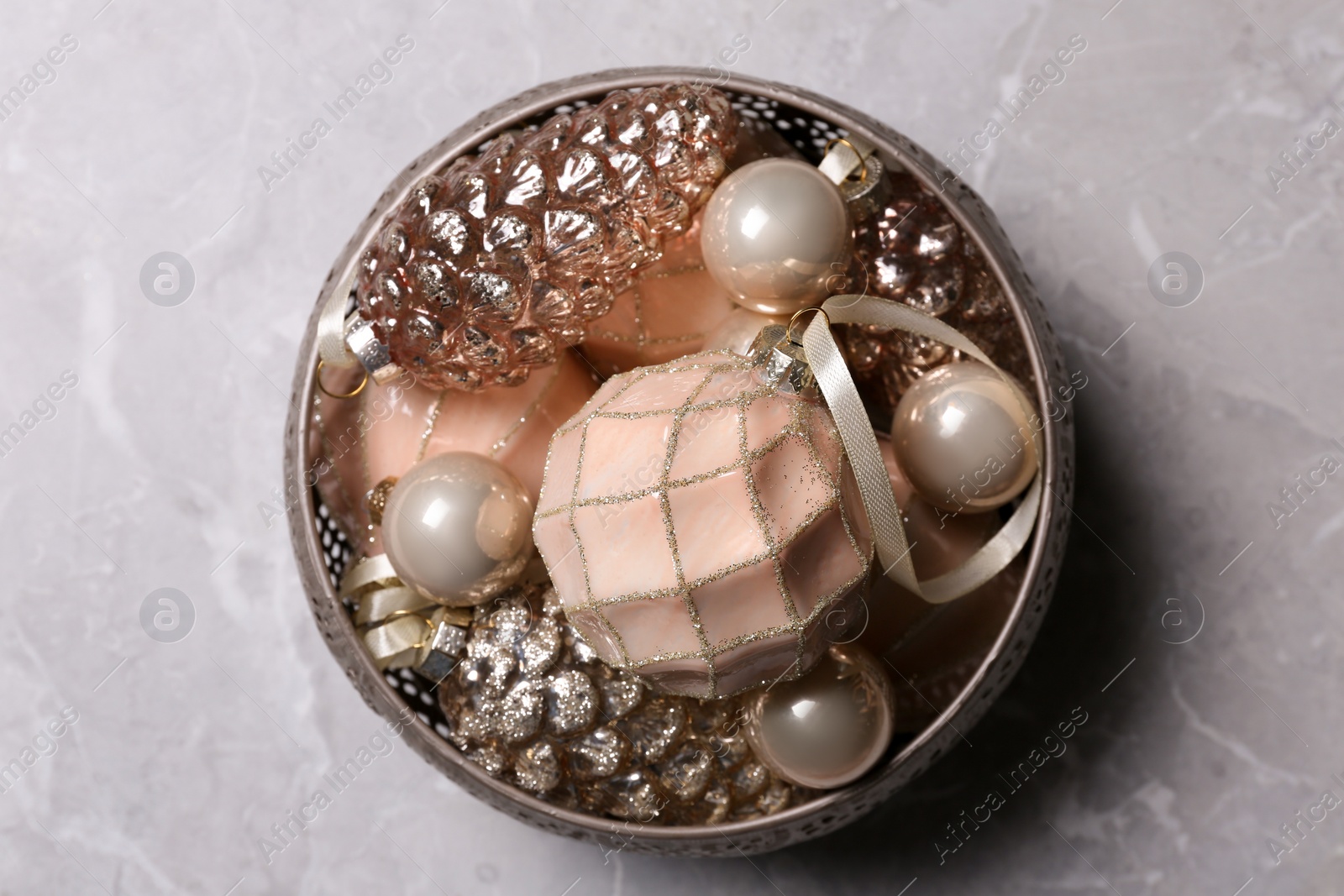 Photo of Christmas baubles in bowl on light grey table, top view