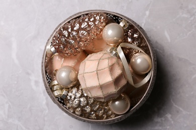 Christmas baubles in bowl on light grey table, top view
