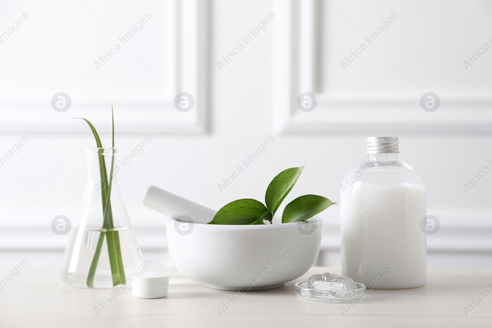 Photo of Natural ingredients for cosmetic products and laboratory glassware on white table