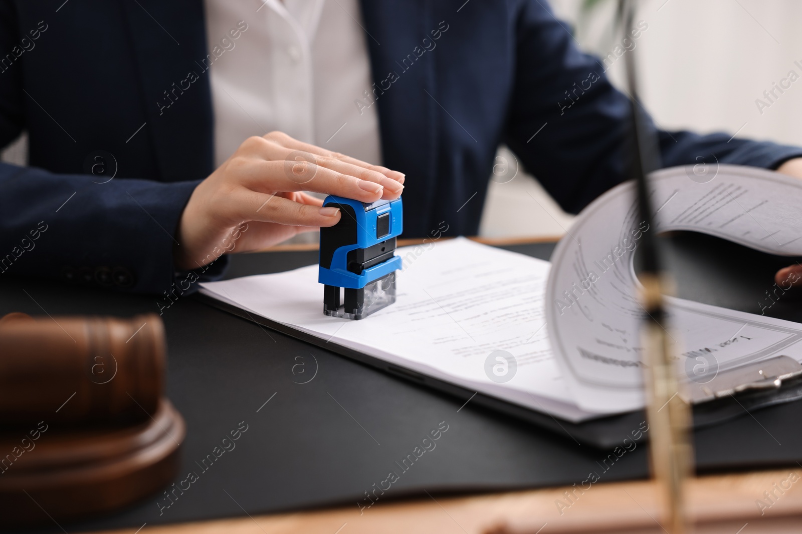 Photo of Notary stamping document at table in office, closeup