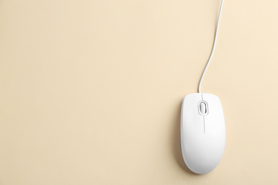 Modern wired optical mouse on beige background, top view. Space for text