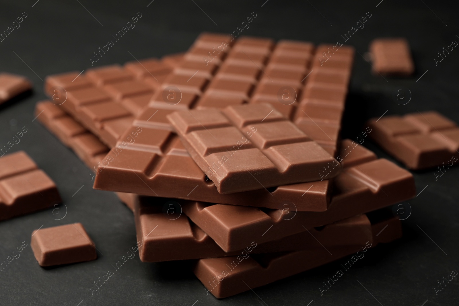 Photo of Pieces of tasty chocolate on grey table, closeup