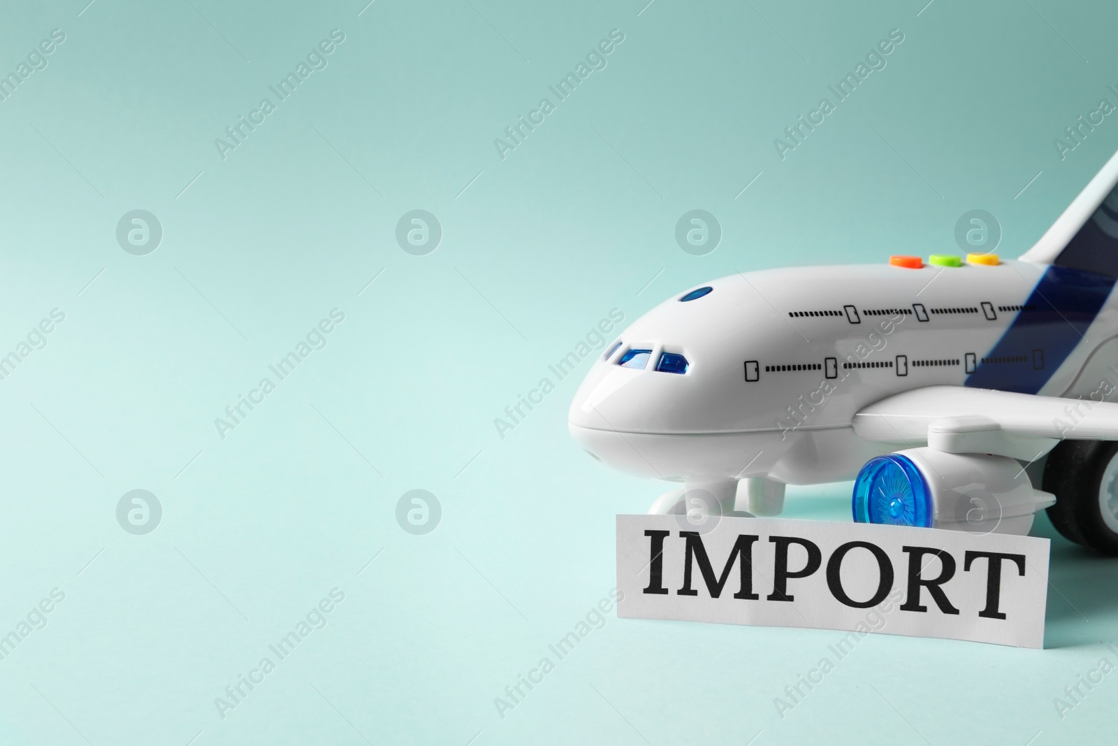 Photo of Card with word Import and toy plane on light blue background, space for text