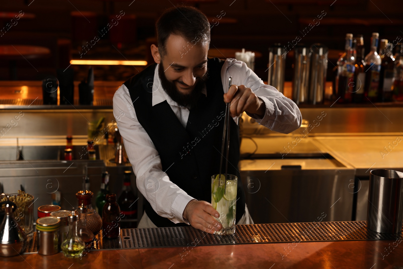 Photo of Bartender making fresh alcoholic cocktail at bar counter