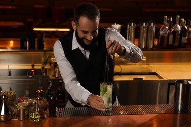 Bartender making fresh alcoholic cocktail at bar counter