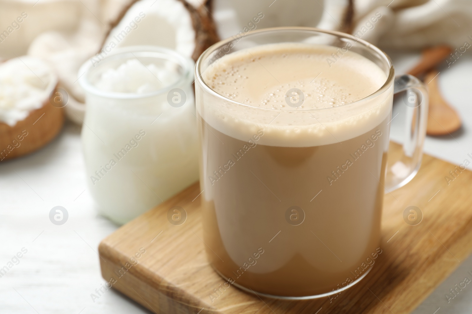 Photo of Delicious coffee with organic coconut oil on white wooden table