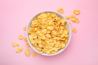 Photo of Breakfast cereal. Tasty corn flakes in bowl on pink table, top view