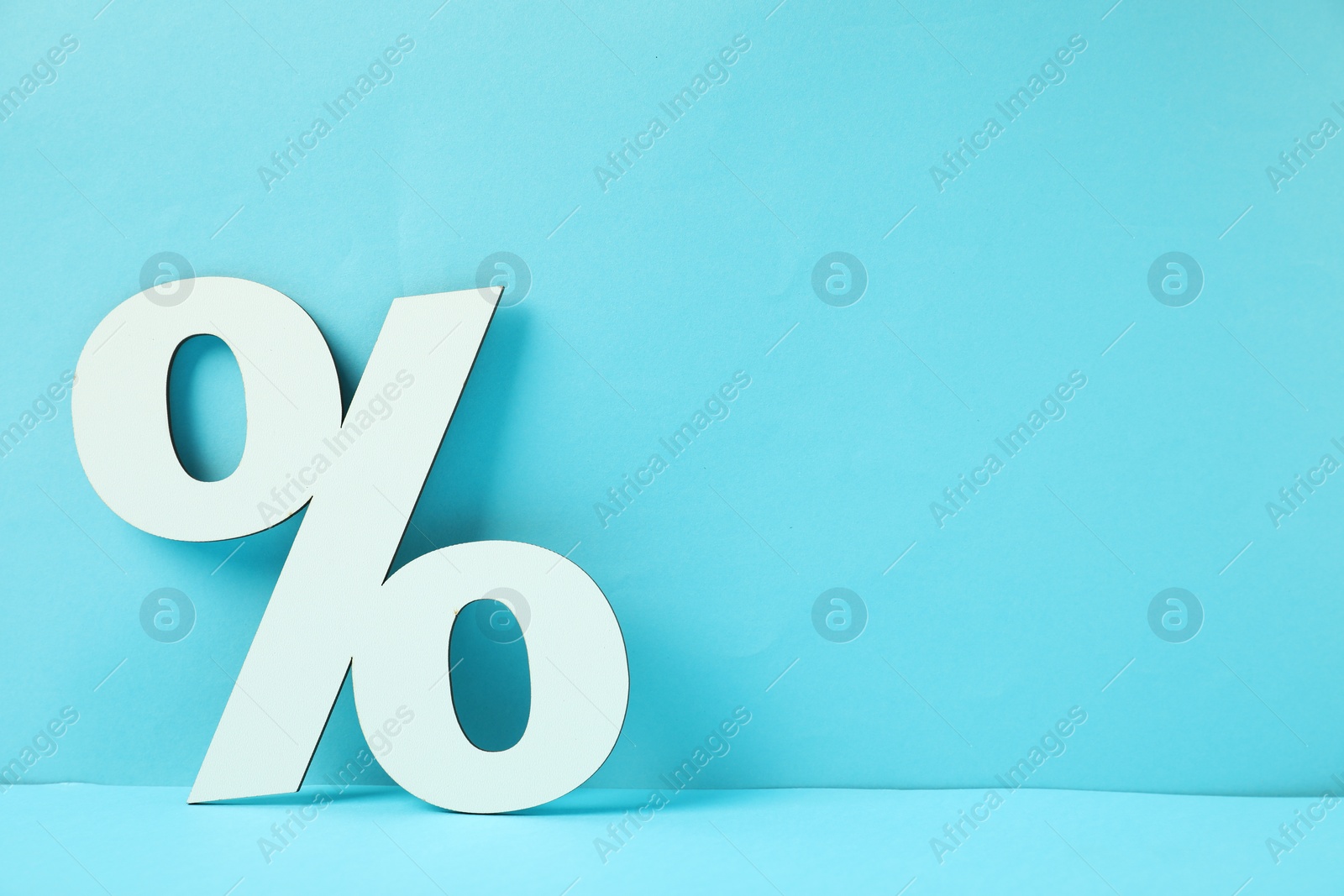 Photo of White percent sign on light blue background. Space for text