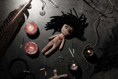 Photo of Female voodoo doll with pin in heart and ceremonial items on grey table, flat lay