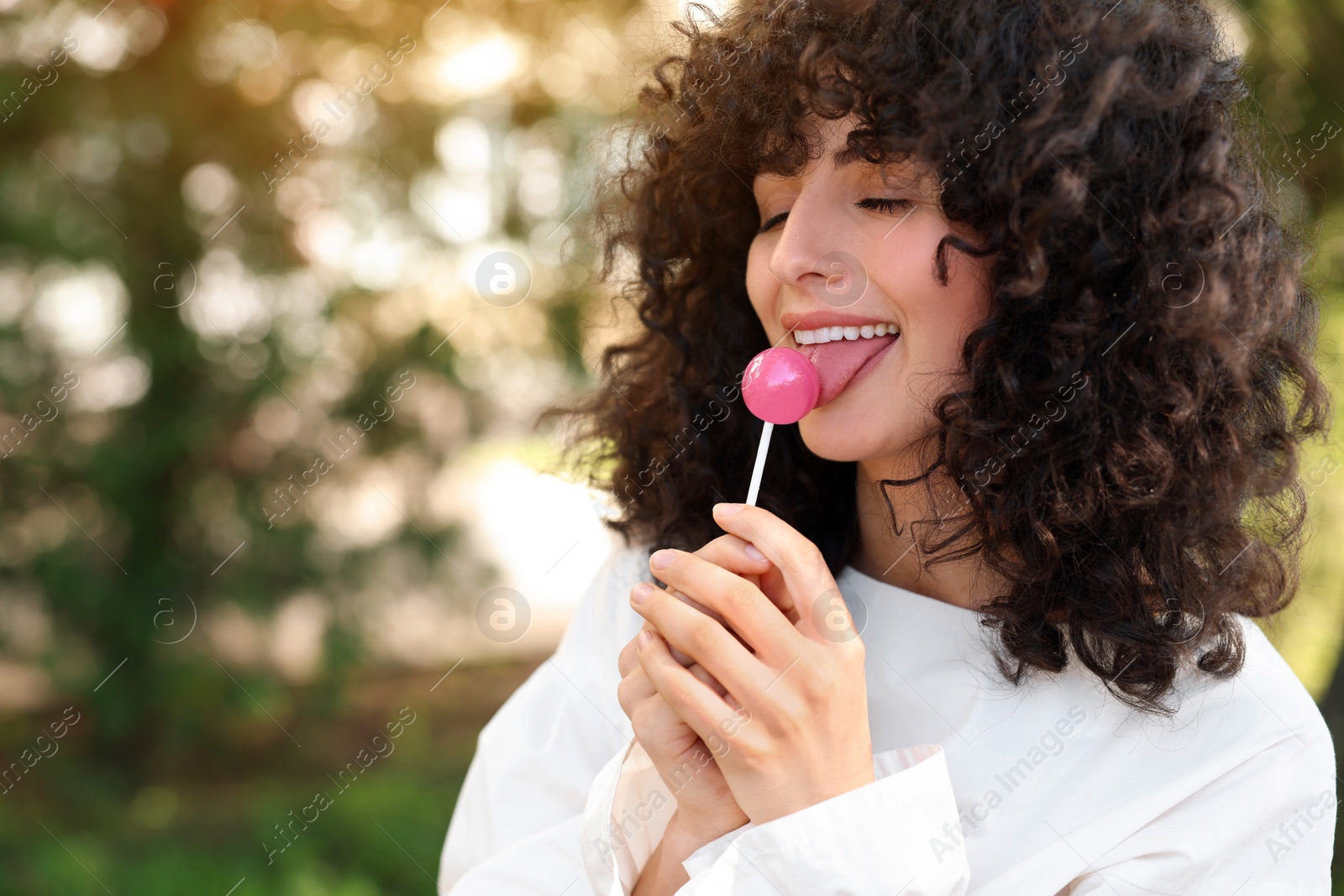 Photo of Beautiful woman with lollipop outdoors, space for text