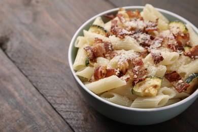 Photo of Tasty pasta with bacon and cheese on wooden table, closeup. Space for text