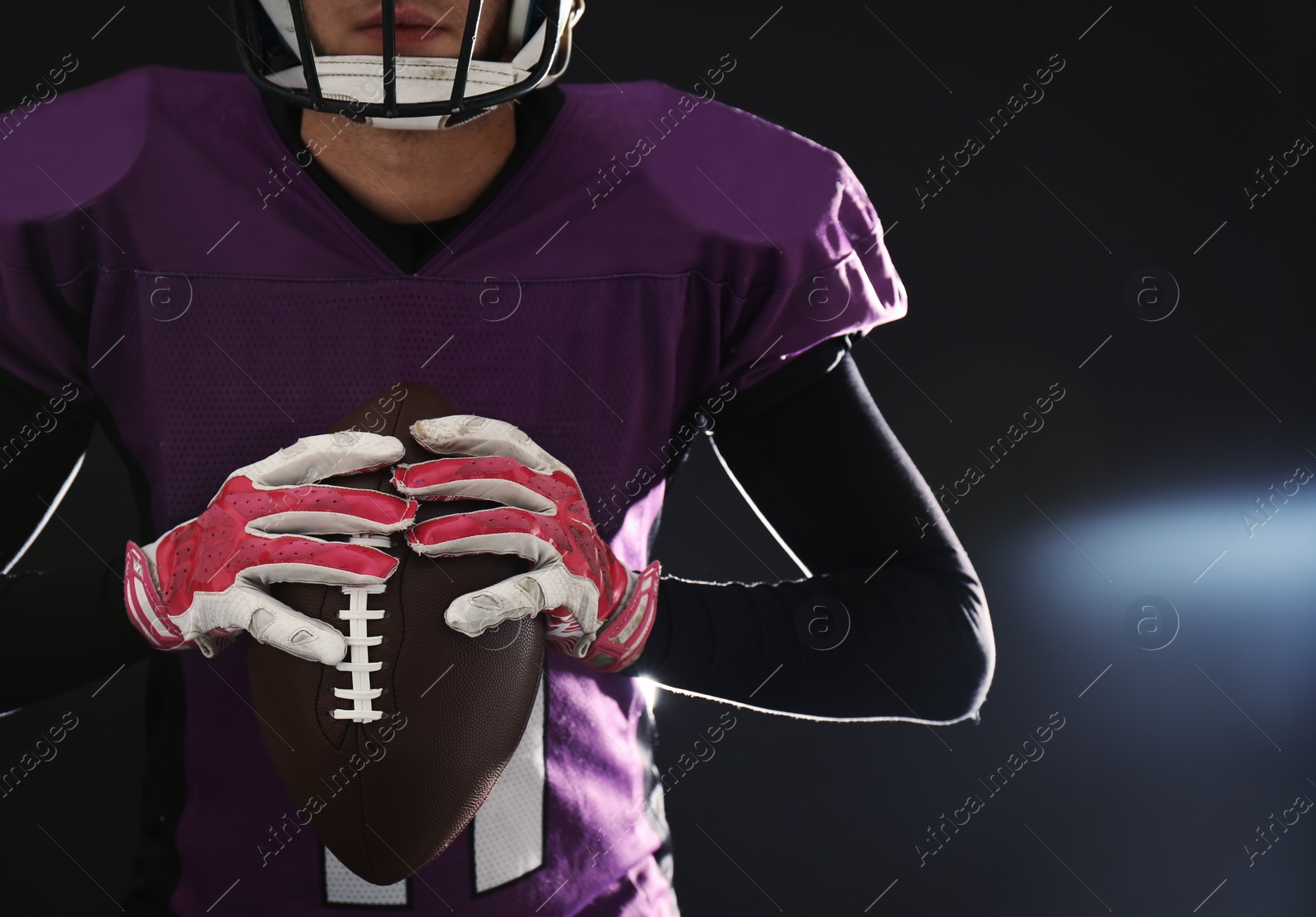 Photo of American football player with ball on dark background