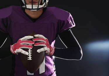 Photo of American football player with ball on dark background