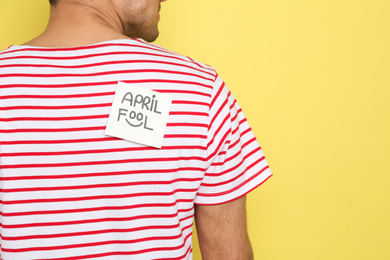 Photo of Man with APRIL FOOL sticker on back against yellow background, closeup