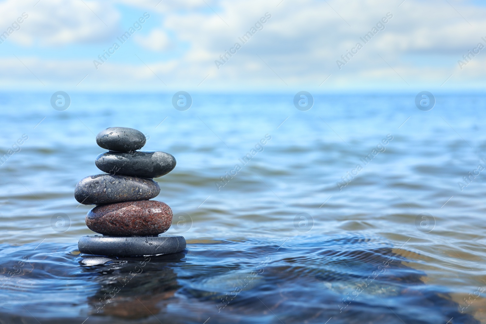 Photo of Stack of stones in sea water, space for text. Zen concept