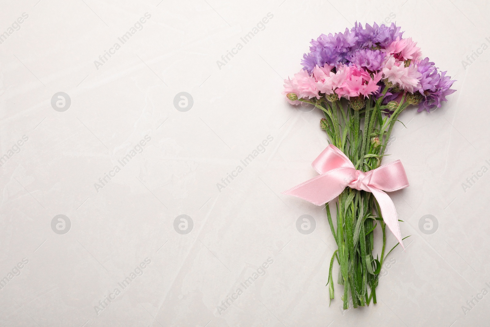 Photo of Bouquet of beautiful cornflowers on light table, top view. Space for text