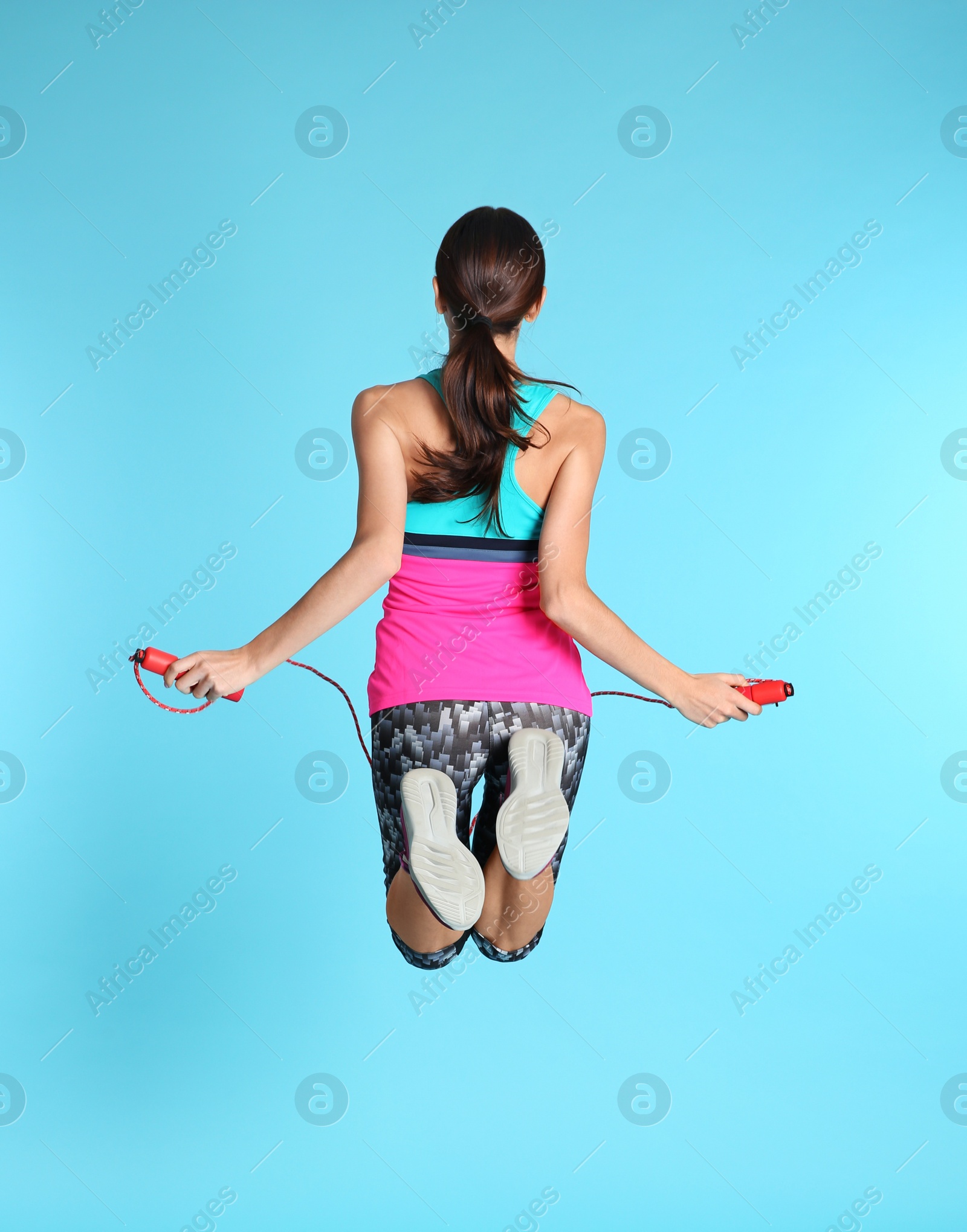 Photo of Young sportive woman training with jump rope on color background