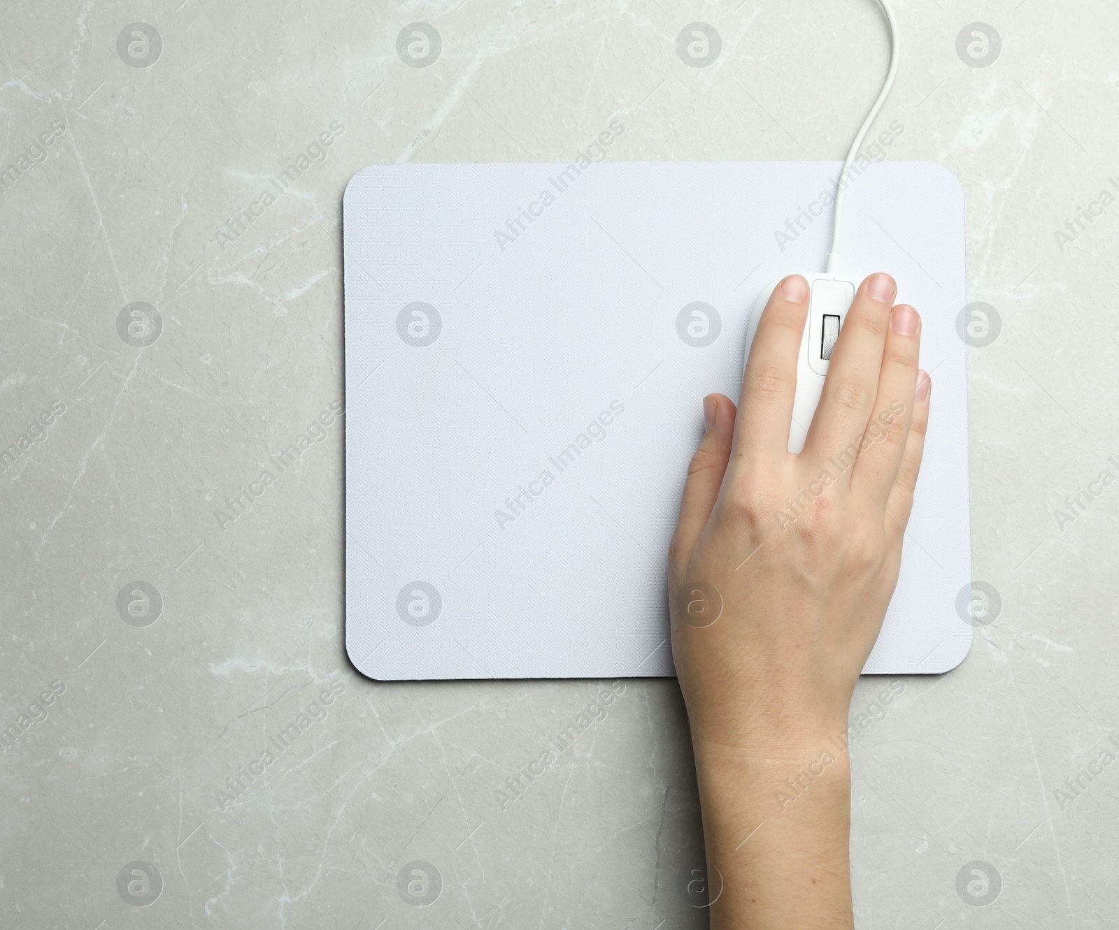 Photo of Woman using wired computer mouse on light grey marble table, top view. Space for text