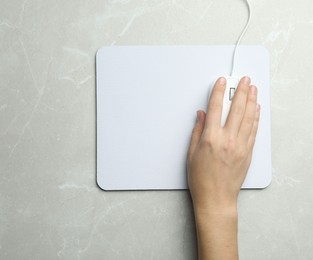 Photo of Woman using wired computer mouse on light grey marble table, top view. Space for text