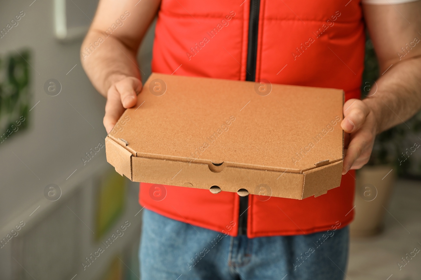 Photo of Man with pizza box indoors, closeup. Food delivery service