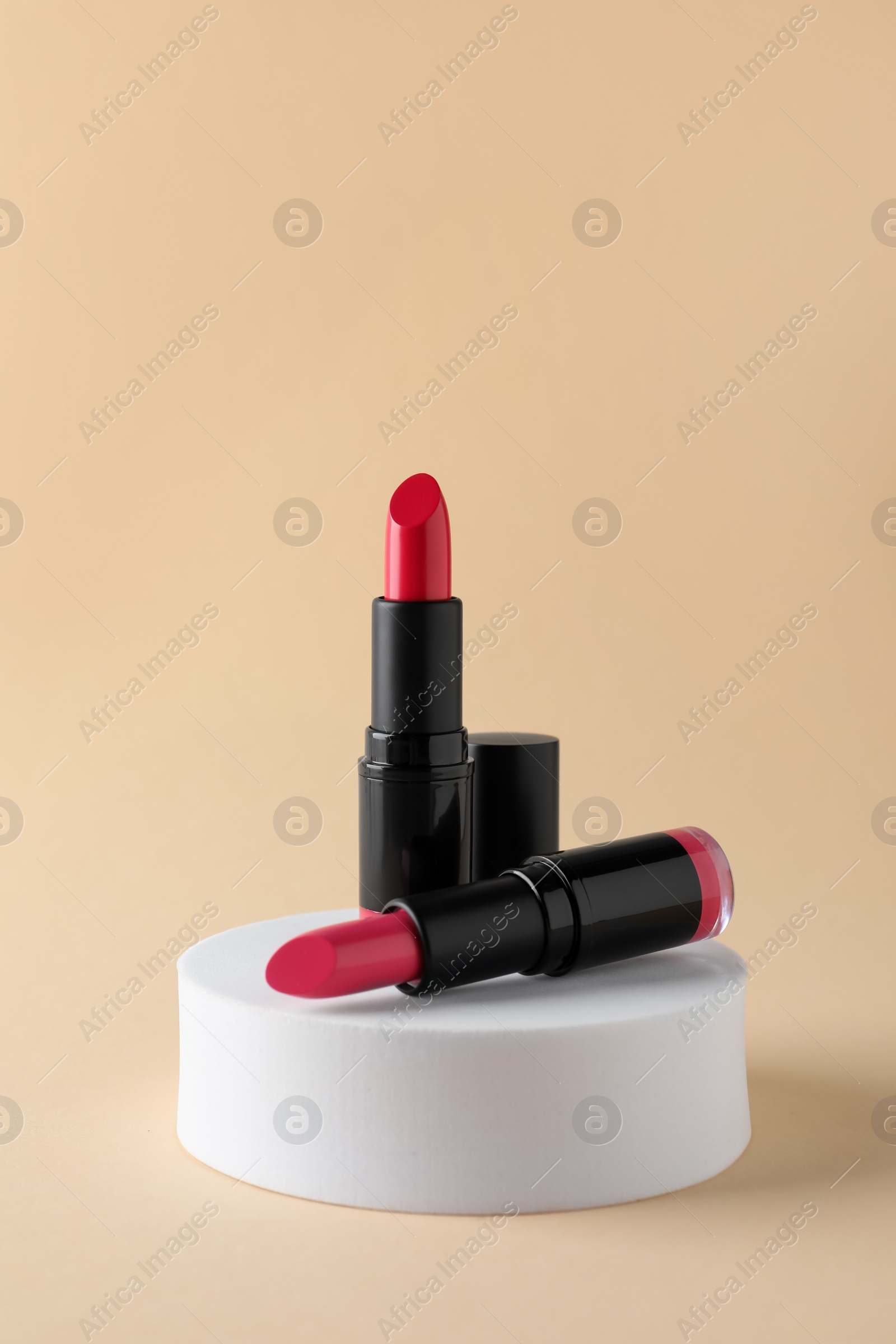 Photo of Beautiful glossy pink lipsticks on beige background