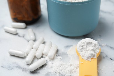 Photo of Amino acid pills and powder on white marble table, closeup