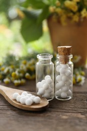 Photo of Bottles of homeopathic remedy and flowers on wooden table