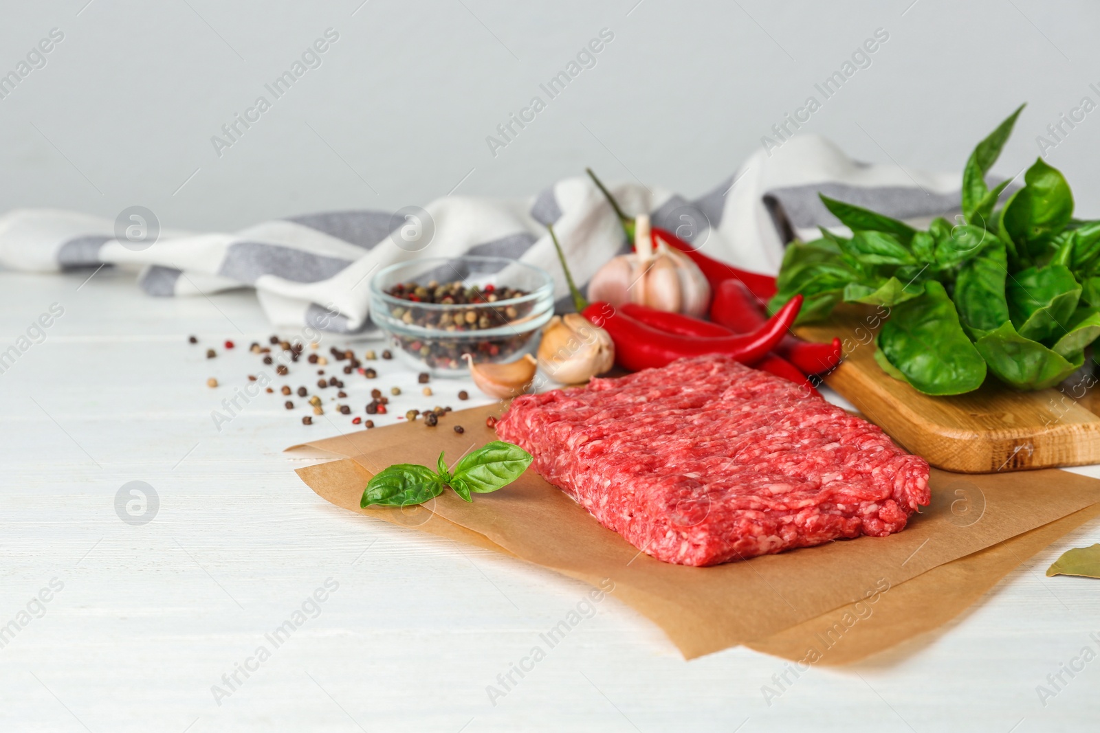 Photo of Fresh raw minced meat and vegetables on white wooden table