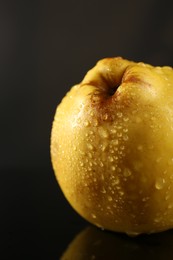 Photo of Tasty ripe quince with water drops on black background, closeup