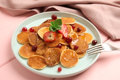 Cereal pancakes with berries on pink wooden table