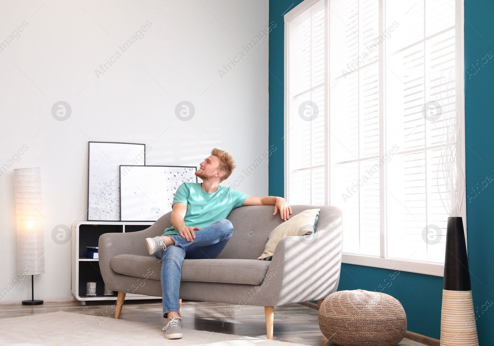 Photo of Happy young man resting on sofa under air conditioner at home