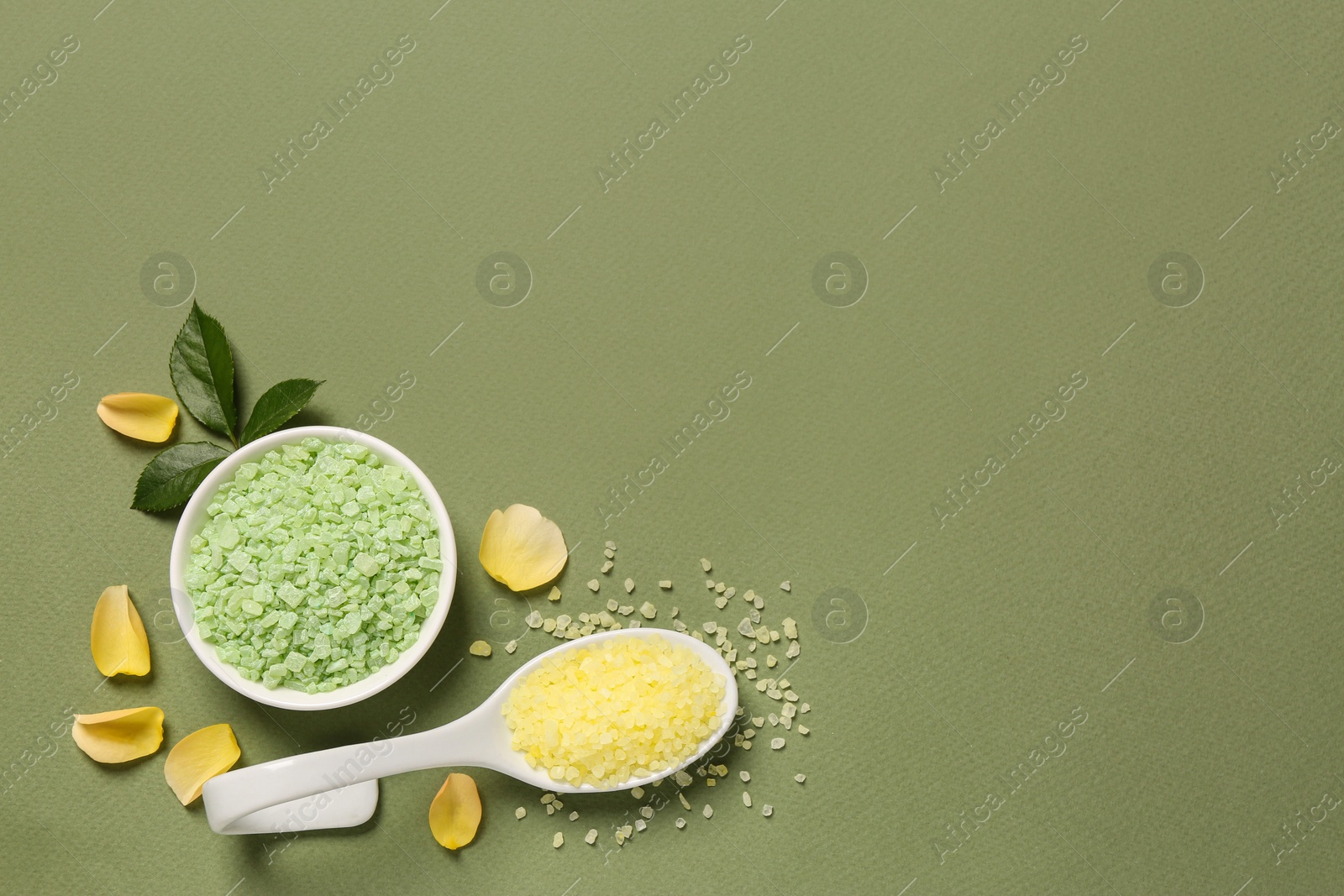 Photo of Bowl and scoop with sea salt, rose petals on olive background, flat lay. Space for text