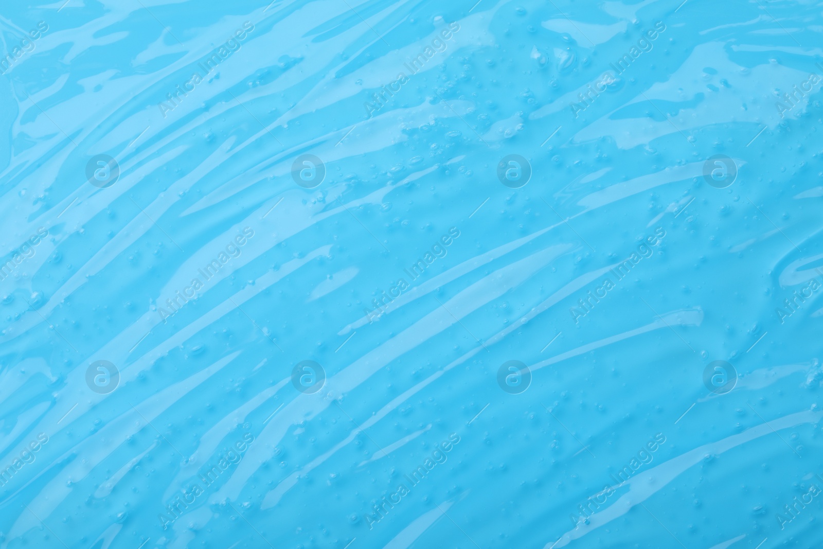 Photo of Pure transparent cosmetic gel on light blue background, closeup