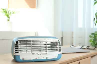 Photo of Modern air purifier on wooden table in room