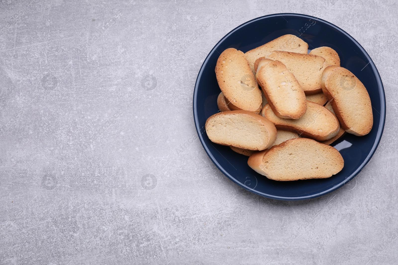 Photo of Plate of hard chuck crackers on light grey table, top view. Space for text