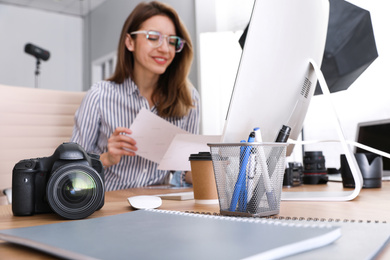 Photo of Professional photographer working at table in office, focus on camera