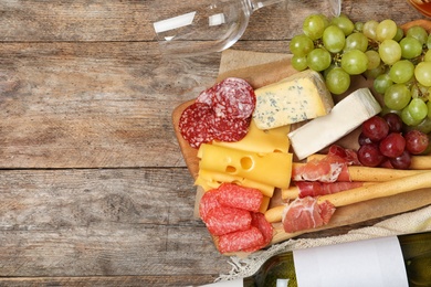 Photo of Flat lay composition with wine, snacks and space for text on wooden background