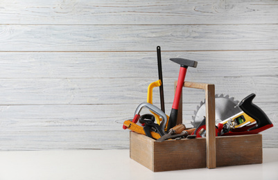 Photo of Box with carpenter's tools on white table. Space for text