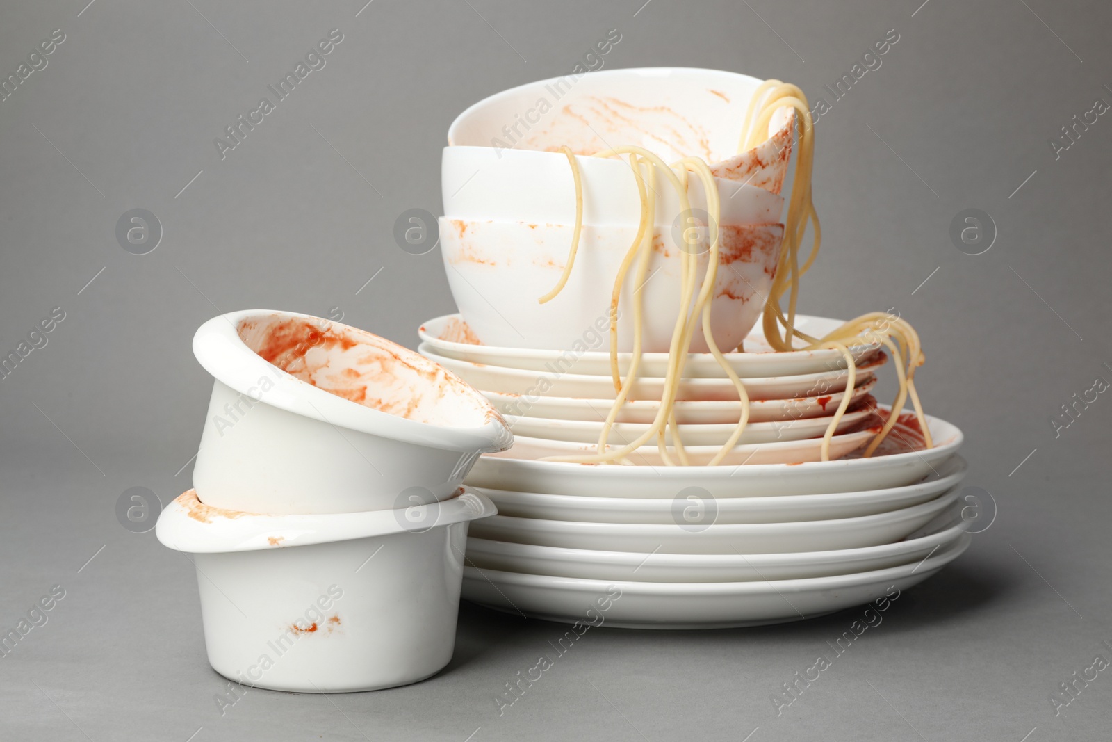 Photo of Set of dirty dishes with spaghetti leftovers on grey background