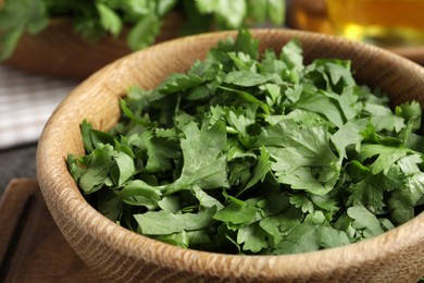 Photo of Cut fresh green cilantro in wooden bowl, closeup