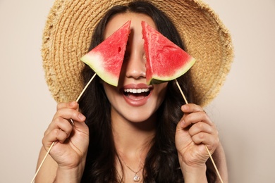 Beautiful young woman with watermelon on beige background