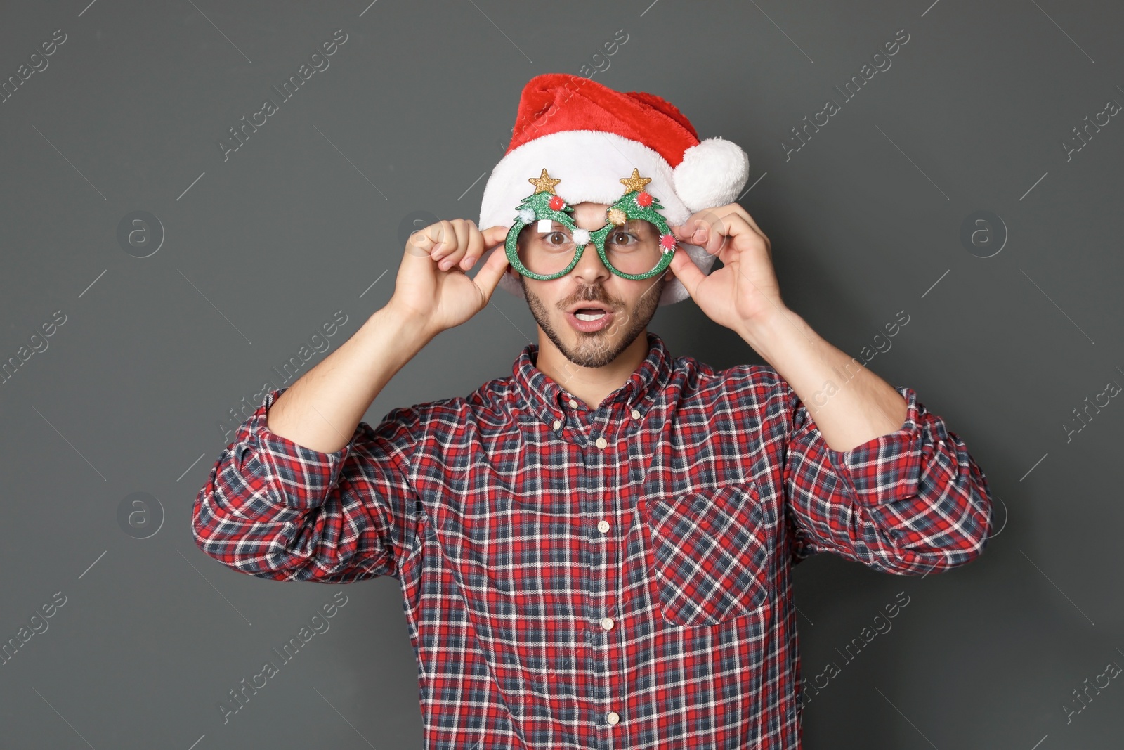 Photo of Young man in Christmas hat on grey background