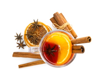 Photo of Glass cup of mulled wine, cinnamon and dried orange slices on white background, top view