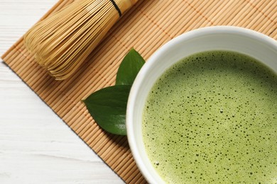Photo of Cup of fresh matcha tea and bamboo whisk on table, top view